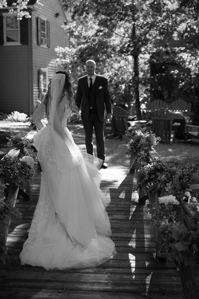 Emotional black and white photo of bride walking toward groom during their outdoor first look.