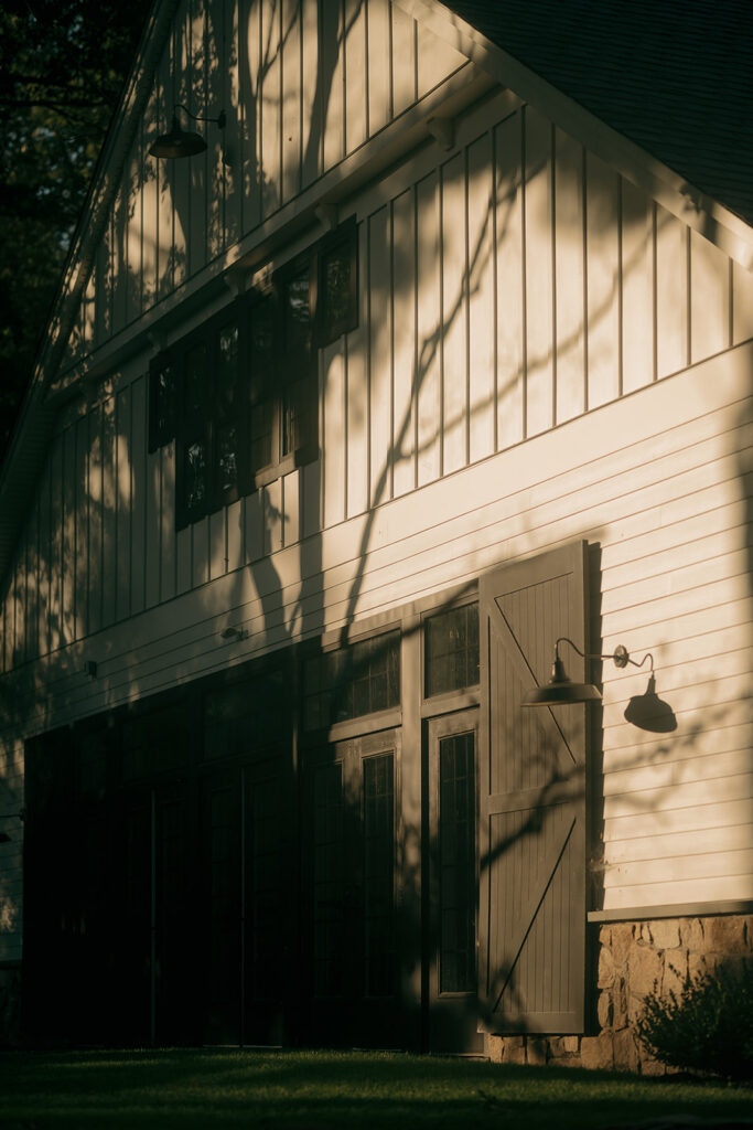 Dramatic golden hour light casting shadows across a white barn wedding venue.