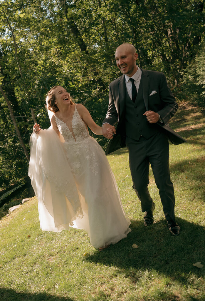 Cinematic wedding photo of a bride and groom running through the grass during their outdoor portraits. 
