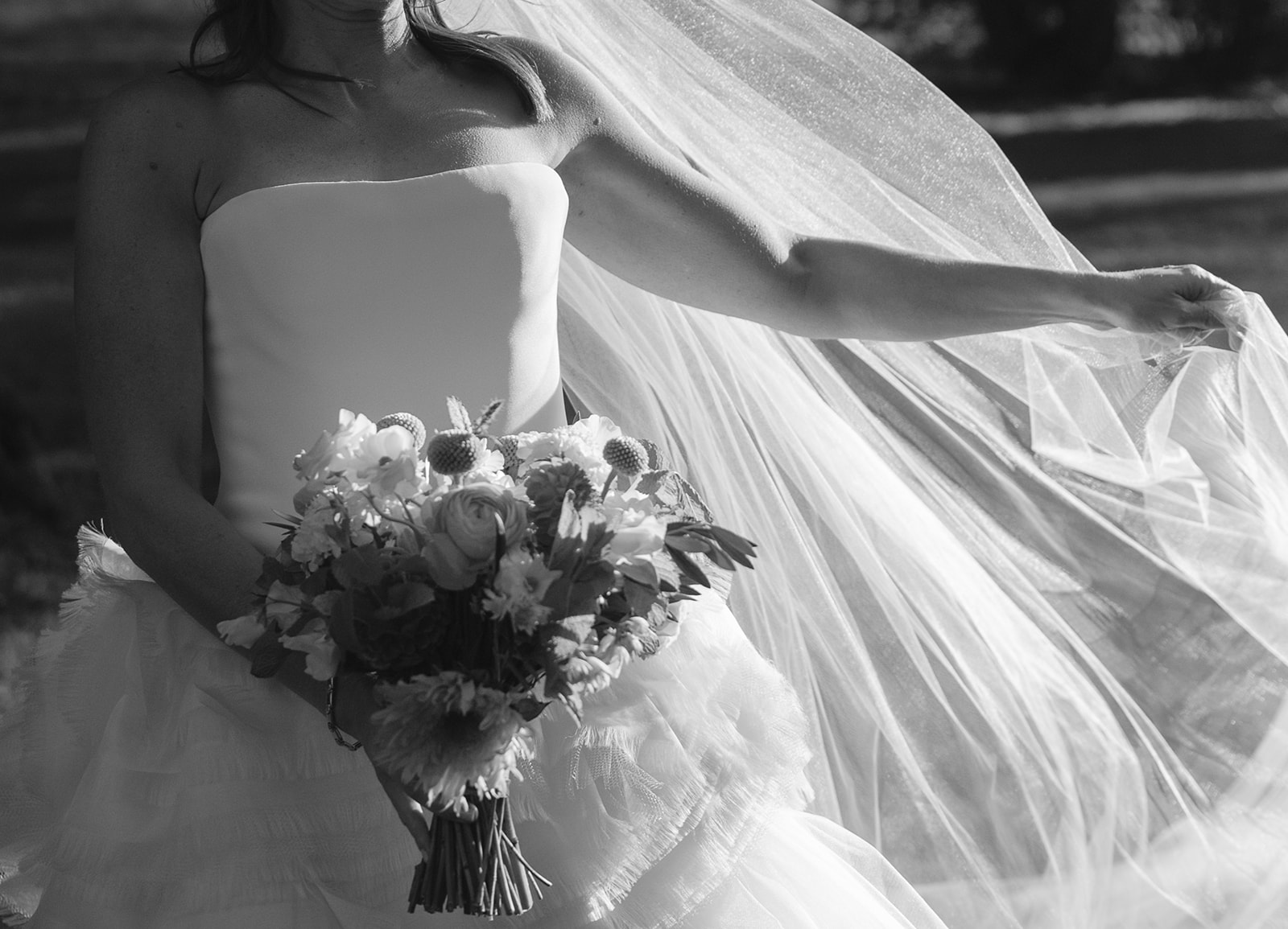 Cinematic wedding photo of a bride holding onto her veil as it blows in the wind. 