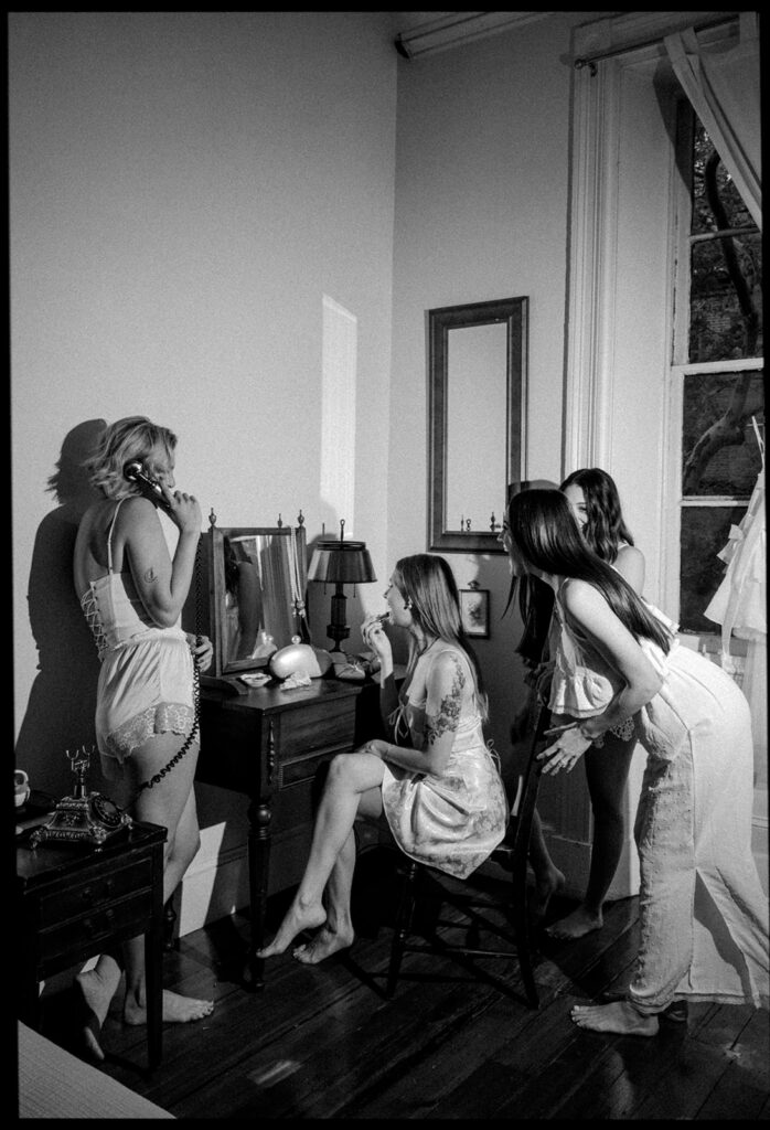 Black and white flash photo of a bride putting her makeup on at a vanity station at Vaux Studio for getting ready wedding photos in Philadelphia.
