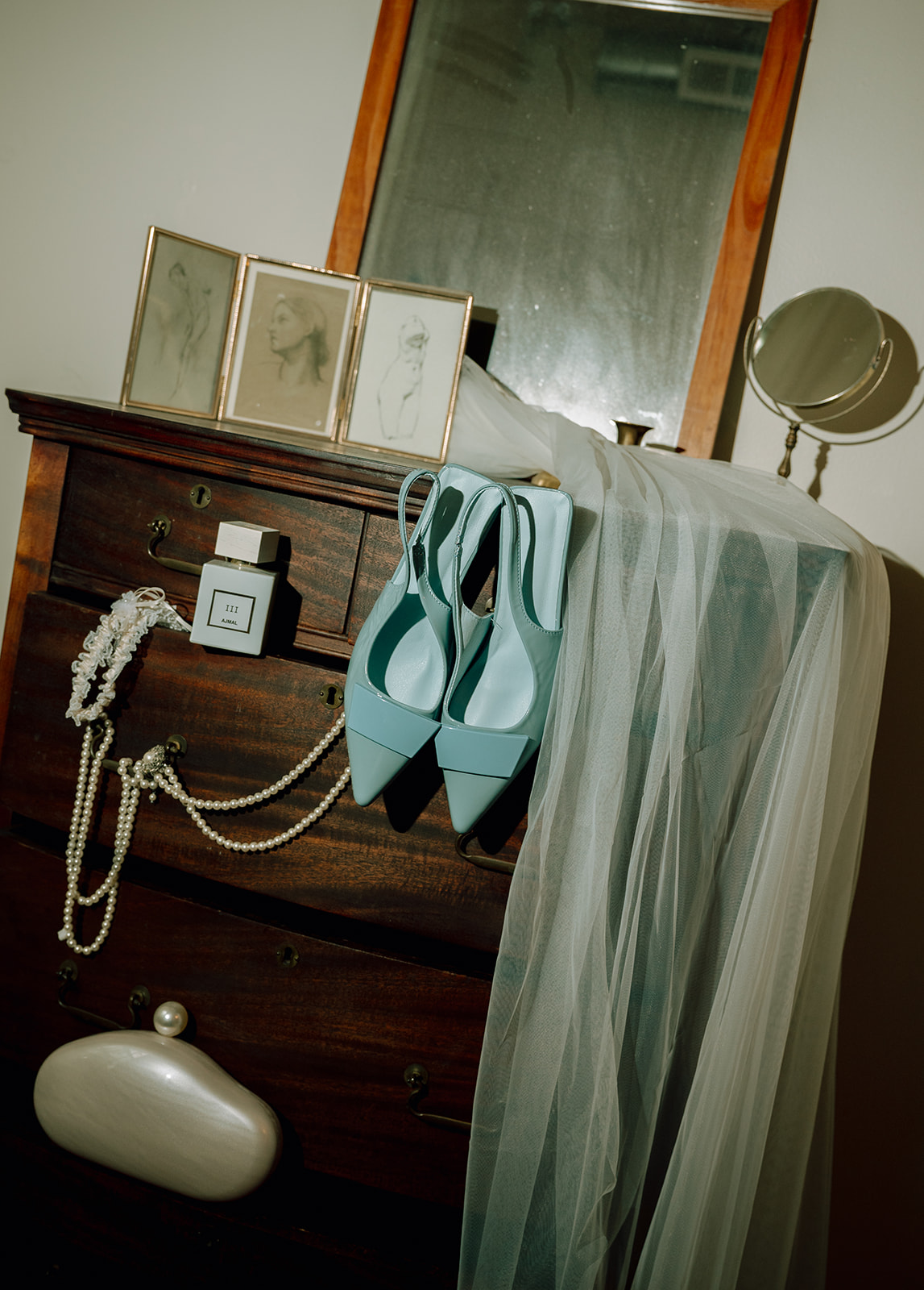Flash photo of brides wedding details with blue shoes, perfume, pearls, garter, and veil. 