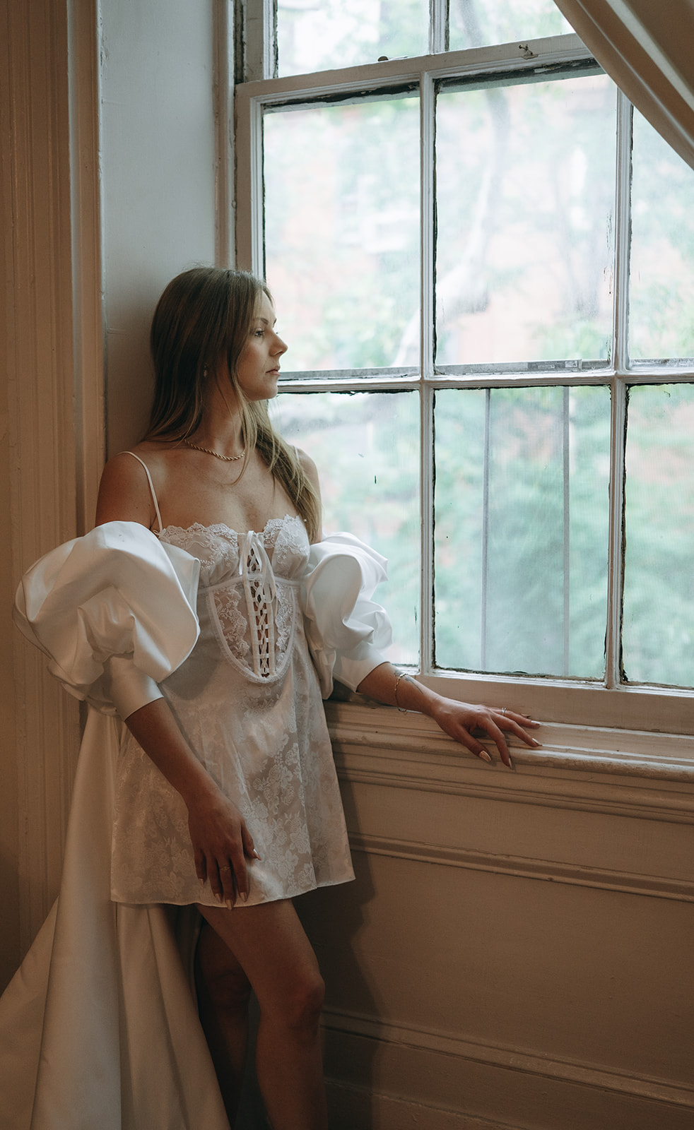 Bride posing by a large window with natural lighting at Vaux Studio in Philadelphia.