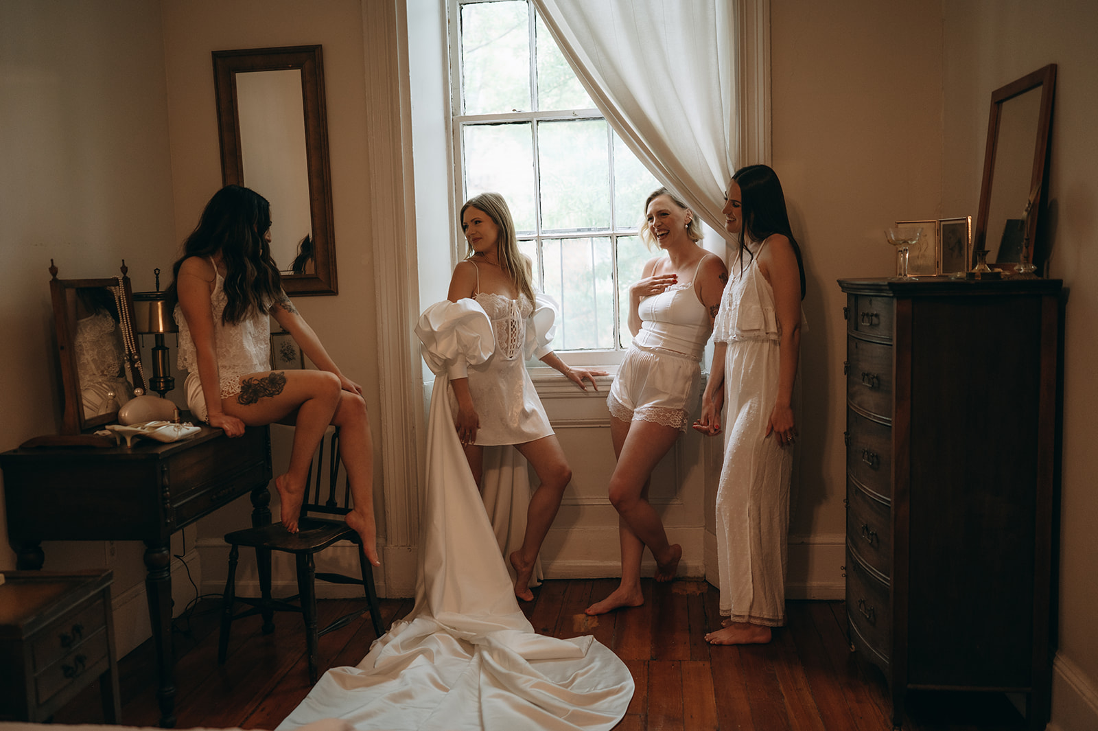 Bride getting ready by a window with her friends at Vaux Studio in Philadelphia.