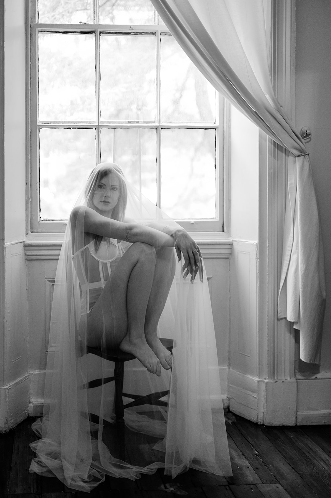 Romantic black and white getting ready wedding photo of a bride sitting in a chair under her veil and in lingerie at Vaux Studio in Philadelphia.