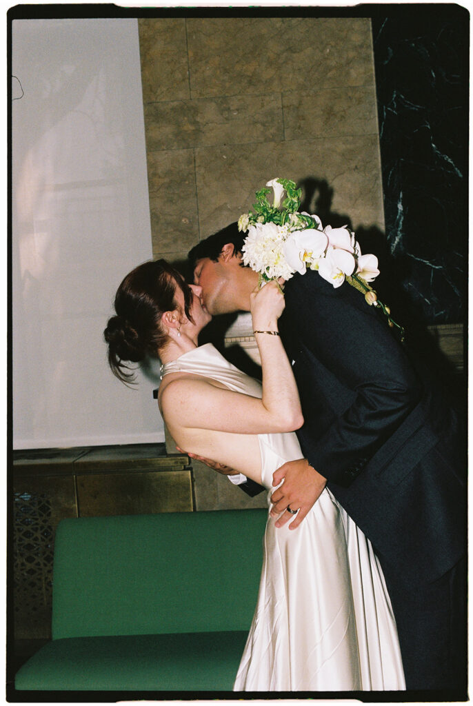 Film photo of a couple kissing in the lobby for their NYC City Hall elopement.