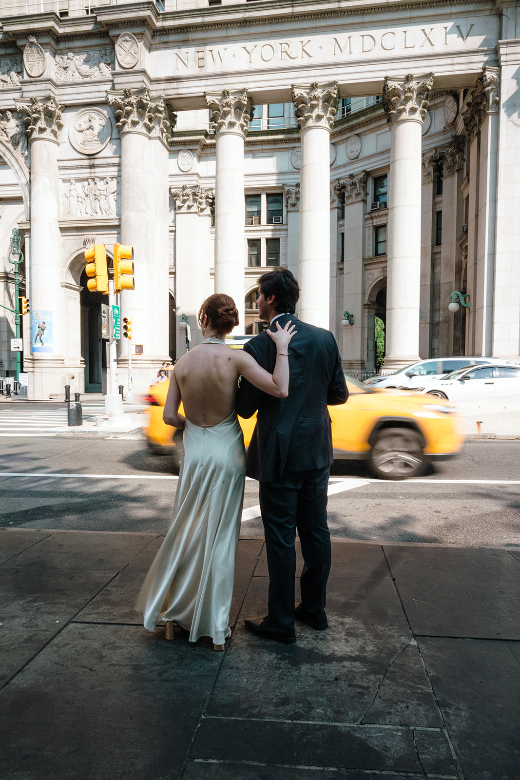 Bride and groom posing downtown while cars drive by. 