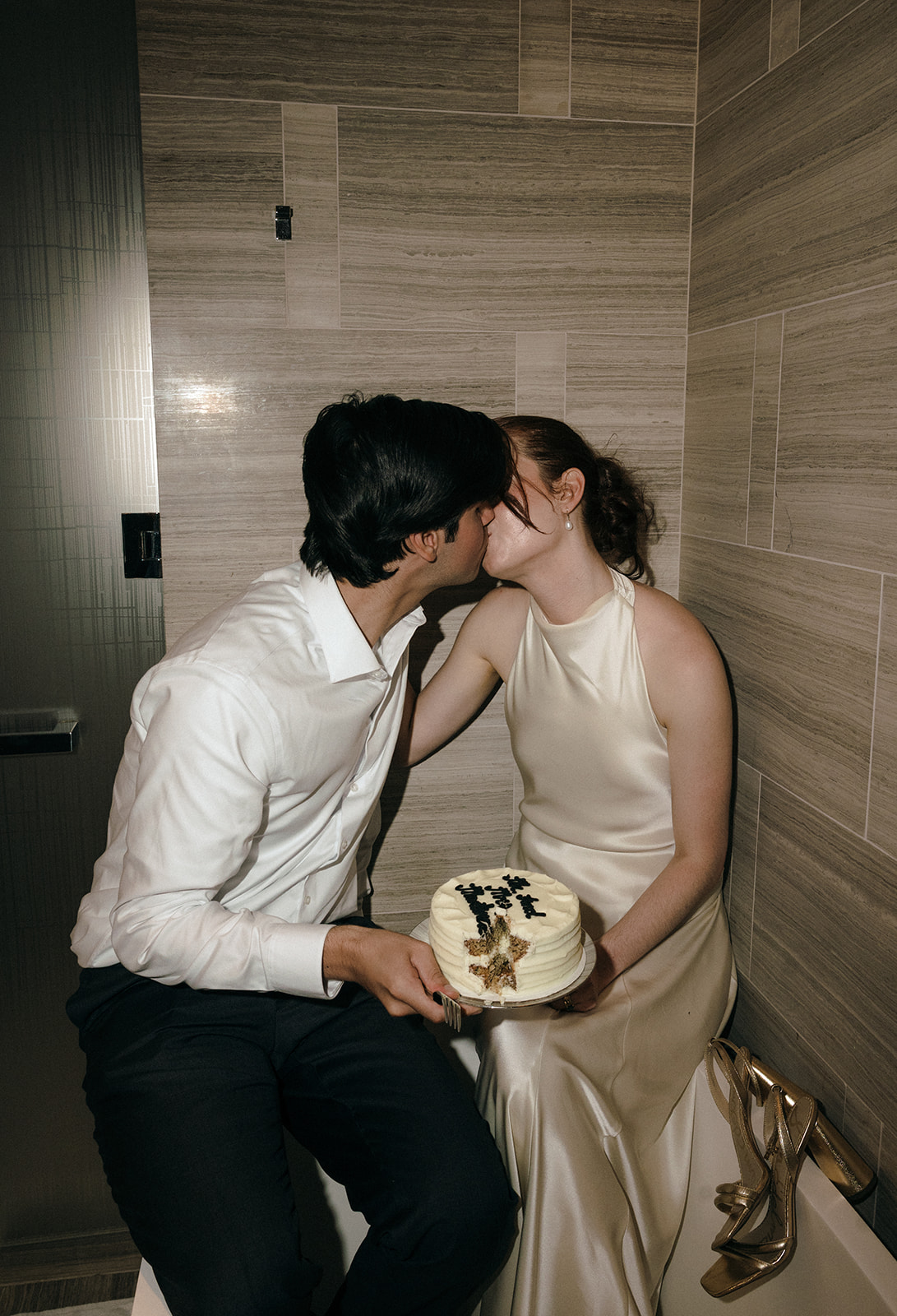 Bride and groom kissing with a cake in hand at their hotel.