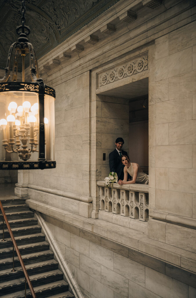 Bride and groom leaning on a balcony at The New York Public Library.